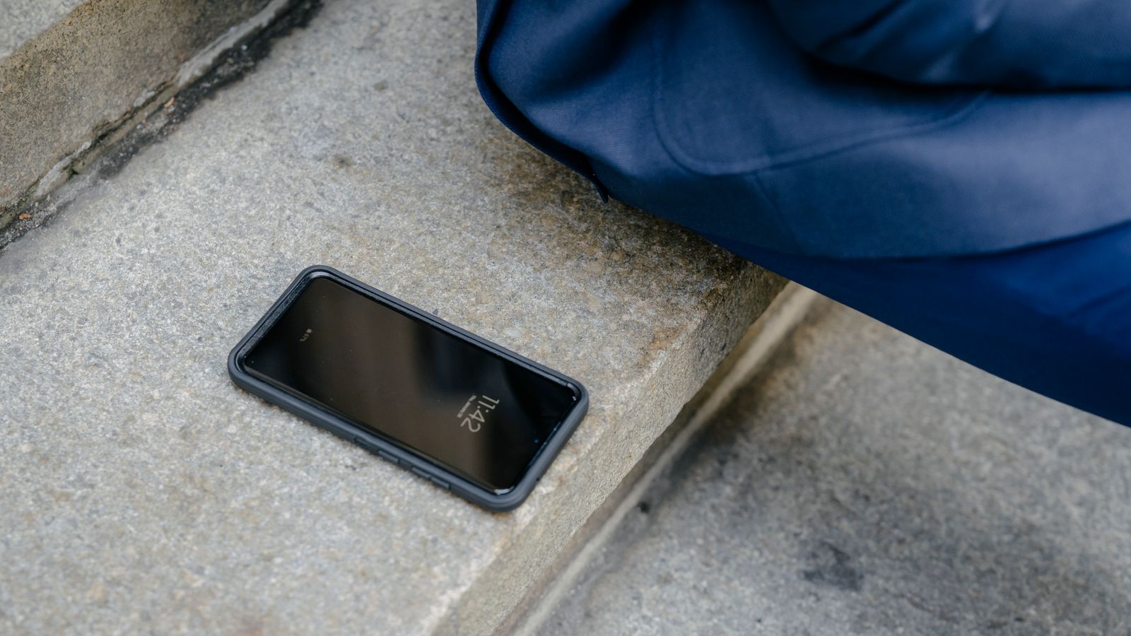 Un smartphone laissé sans surveillance sur des marches en pierre, à côté d'une personne assise