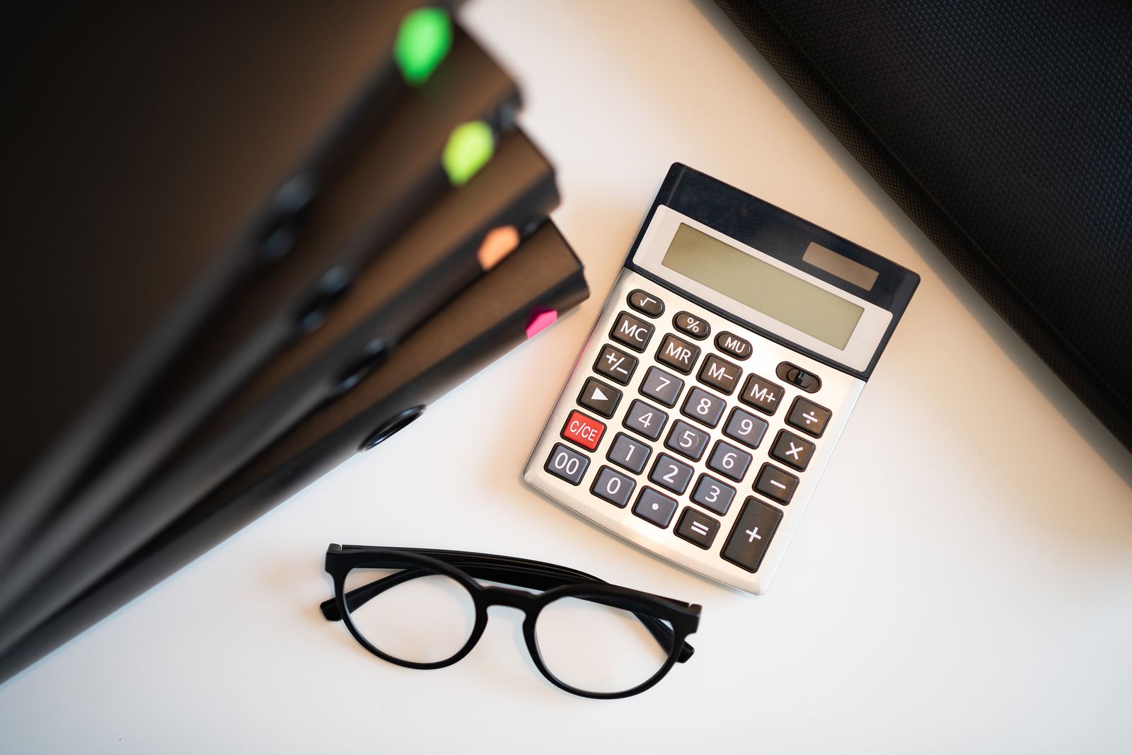 Calculatrice, lunettes de lecture et dossiers sur un bureau