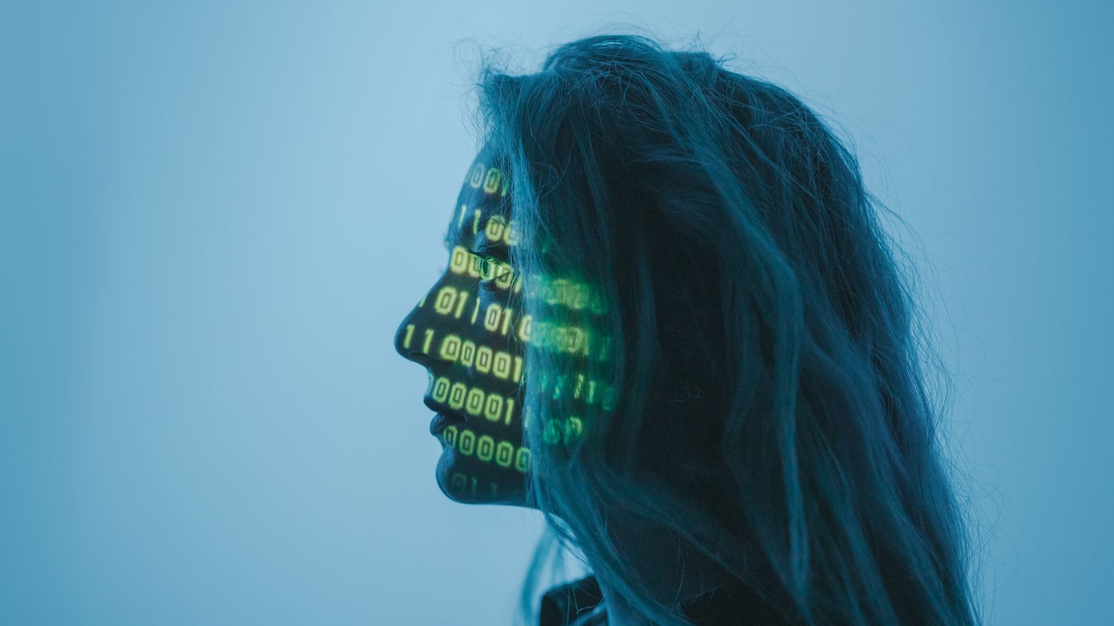 Profil d'une femme sur le visage de laquelle est projeté du code binaire