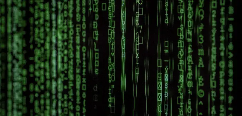 Hacker encagoulé devant un ordinateur dans une pièce sombre - concept de cyberguerre et piratage informatique