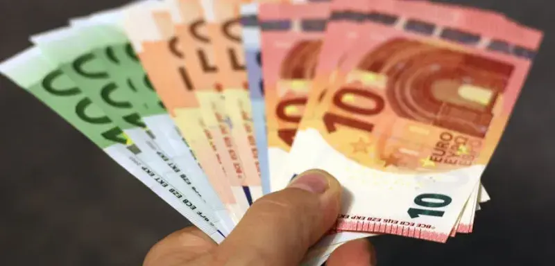 Éventail de billets en euros de différentes coupures tenus dans une main