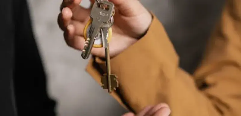 Deux adultes échangeant des clés de maison, symbole de transfert de propriété ou de contrat de location