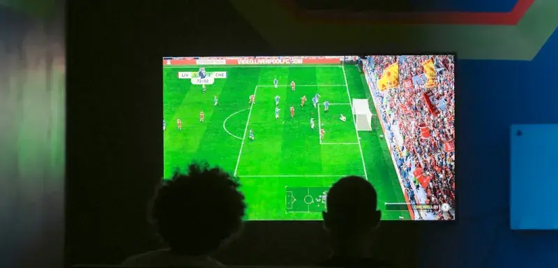 Deux personnes regardant un match de football sur un écran de télévision