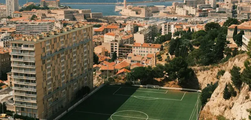 A soccer field overlooks a city and the ocean.