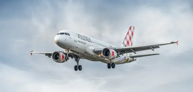 Un avion commercial Volotea en vol dans un ciel nuageux, photographié depuis le sol