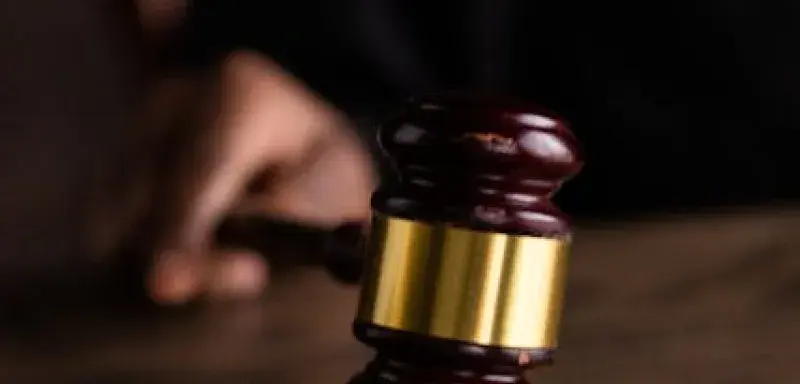 Gros plan sur un marteau de juge posé sur un socle en bois, symbole de la justice et du droit