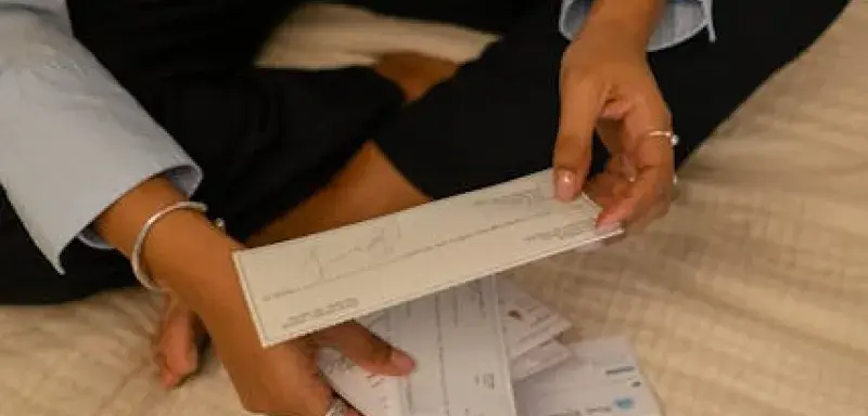 Un particulier assis en tailleur examine des documents fiscaux près de son ordinateur portable