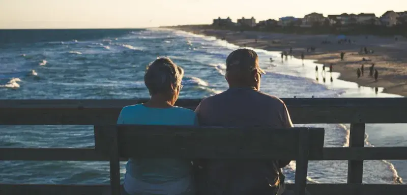 Couple de retraités assis sur un banc face à la mer