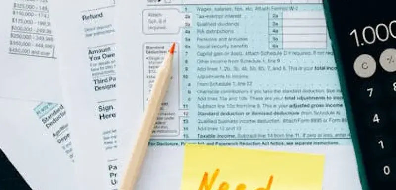 Gros plan sur des formulaires fiscaux avec une calculatrice et un mot demandant de l'aide