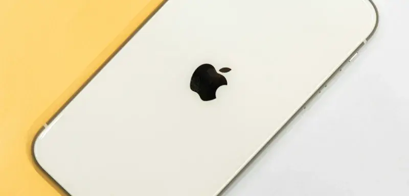 iPhone argenté posé sur une table blanche