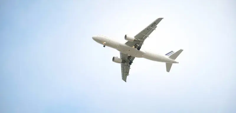 Un avion commercial blanc volant haut dans un ciel bleu dégagé