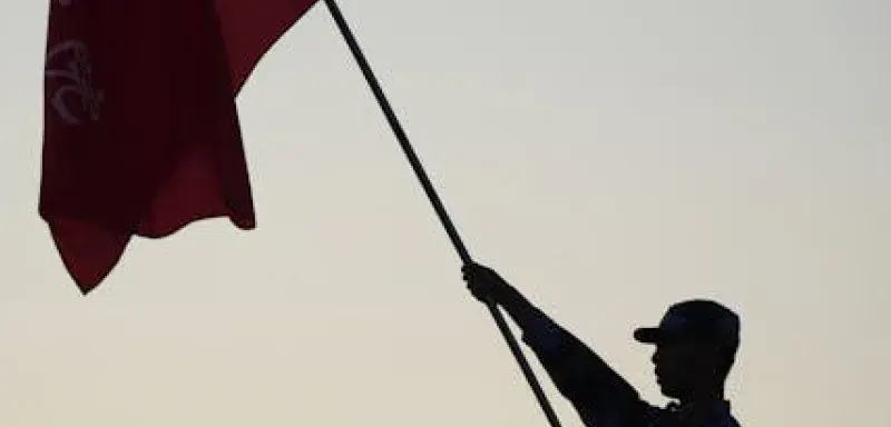 Silhouette d'un soldat brandissant un drapeau au coucher du soleil, évoquant patriotisme et unité
