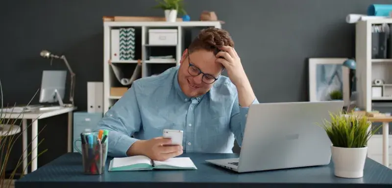 Homme regardant son téléphone portable avec la main dans les cheveux