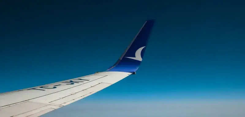 Aile d'avion survolant les nuages et la terre