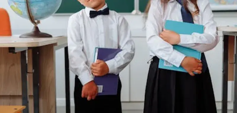 Deux enfants en uniforme scolaire tenant des livres dans une salle de classe