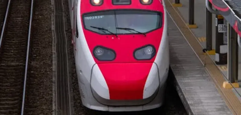 Vue aérienne d'un train rouge et blanc à grande vitesse arrivant en gare