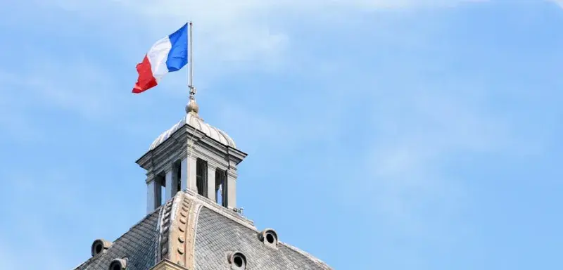 Le drapeau français flotte au sommet d'un dôme d'architecture historique à Paris