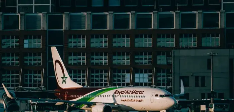 Royal Air Maroc aircraft parked at an airport apron with terminal building in the background.