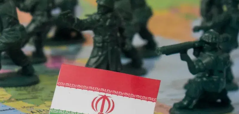 Toy soldiers surround the flag of iran on a map.