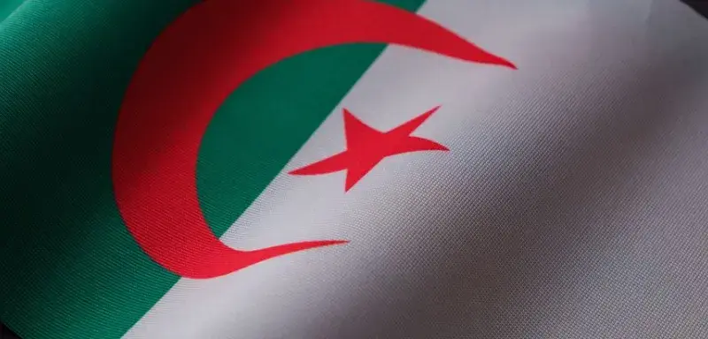 Closeup of the Algerian flag displaying its emblem on textured fabric.