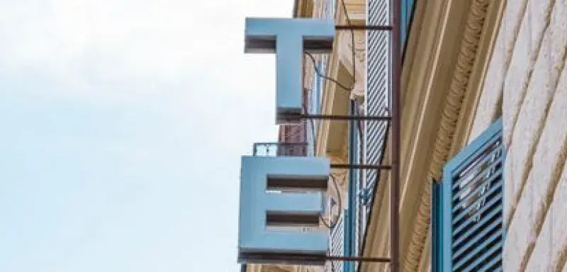 Classic vertical shot of Hotel Saturnia sign and shutters on brick facade.