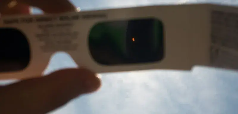 person's hand holding white 3D sunglasses