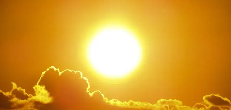 A stunning view of the golden sun shining through clouds at sunset, casting a warm glow.