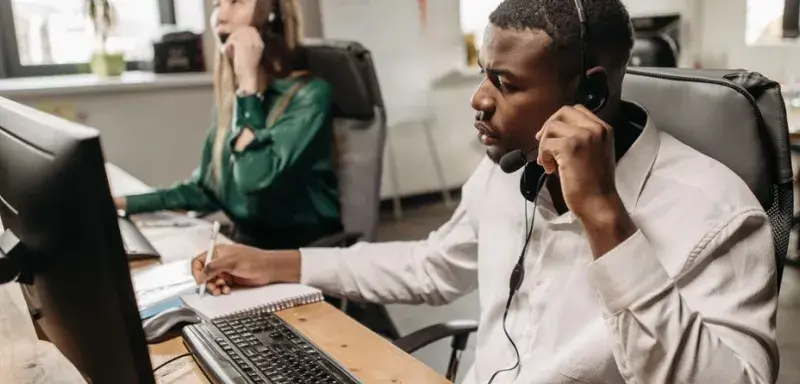 A focused team of customer service representatives working on computers and answering calls in an office