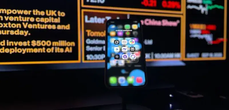 Smartphone displaying AI apps in front of a financial data screen in London.