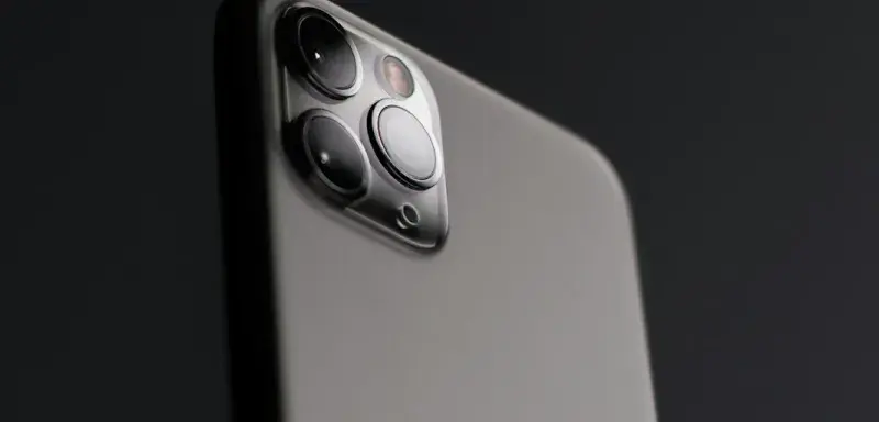A grey smartphone with a triple camera array against a dark background