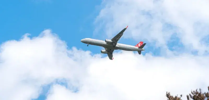 A commercial airplane glides through a clear blue sky with scattered clouds, capturing the essence of aviation travel.