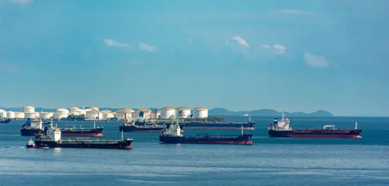 Cargos amarrés près de cuves de stockage de pétrole sur un littoral