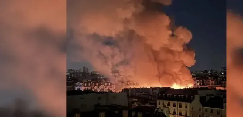 Incendie du marché des Enfants-Rouges à Paris, panache de fumée au-dessus des toits du Marais dans la nuit