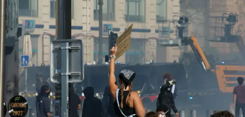 Manifestant debout sur une poubelle brandissant une pancarte lors d'une manifestation de rue