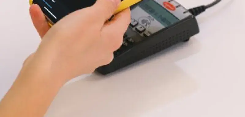 Personne payant avec un smartphone sur un terminal de paiement sans contact