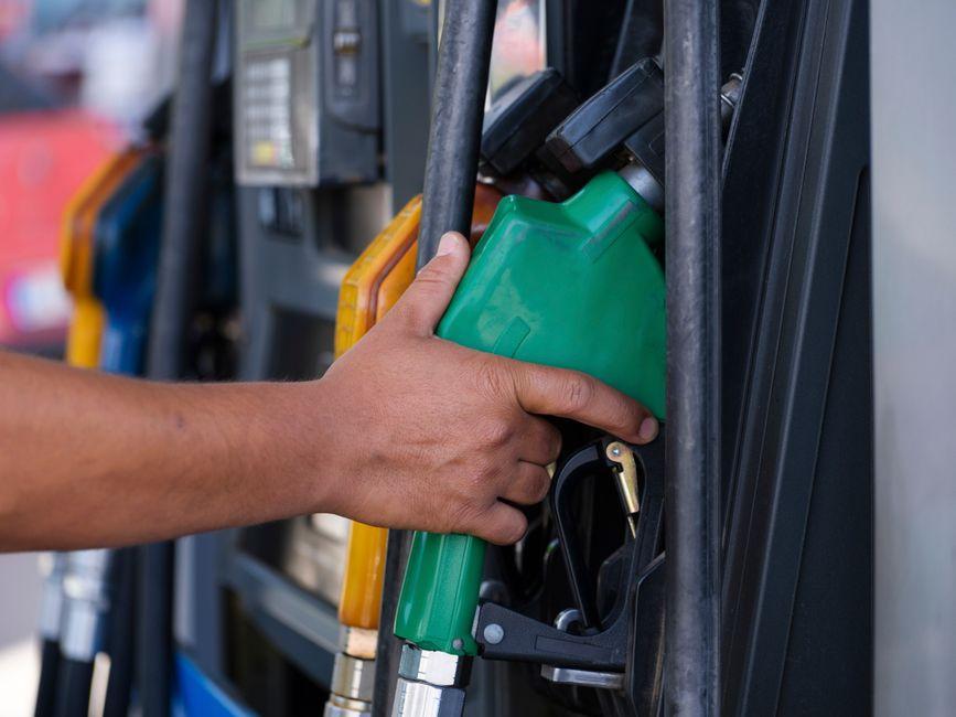 Main tenant un pistolet de pompe à carburant vert dans une station-service