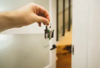 Une main tenant une clé devant une porte de maison
