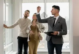 Un couple visite une maison moderne avec un agent immobilier, explorant leur potentiel nouveau logement