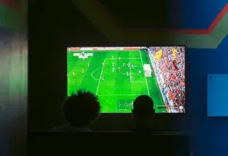 Deux personnes regardant un match de football sur un écran de télévision
