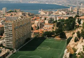 Un terrain de football surplombant une ville et la mer