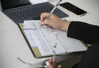 Une personne prenant des notes devant un ordinateur portable lors d'un audit financier