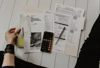 Formulaires fiscaux, stylo et calculatrice posés sur un bureau