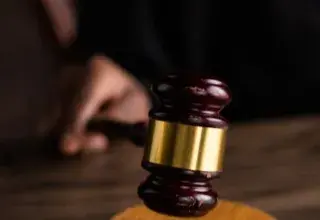 Gros plan sur un marteau de juge posé sur un socle en bois, symbole de la justice et du droit