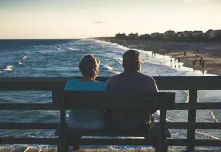 Couple de retraités assis sur un banc face à la mer