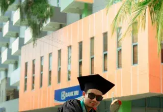 Un homme assis par terre en toge de diplômé