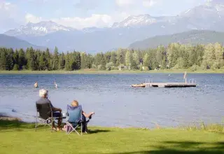 Deux personnes assises sur l'herbe face à un lac, symbolisant une retraite paisible