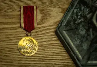 Une médaille d'or avec un ruban rouge et blanc