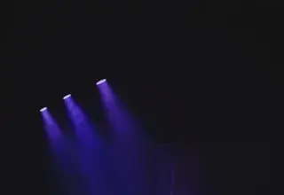 Moody theater scene with purple spotlights casting a vivid glow on an empty stage.