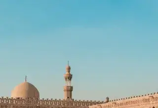 Vue d'une ancienne cour de mosquée au Caire, en Égypte, sous un ciel bleu dégagé, capturant l'architecture islamique