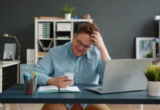 Homme regardant son téléphone portable avec la main dans les cheveux